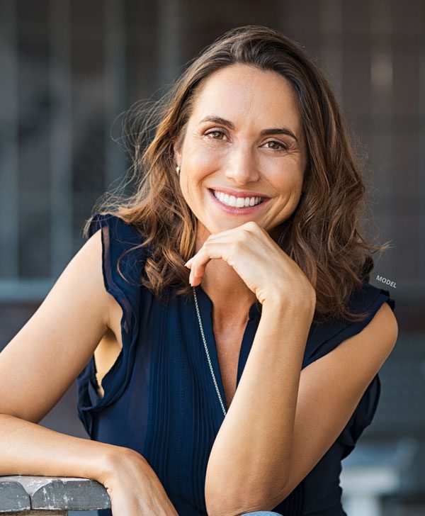 Female model smiling at camera and resting her chin in her hand