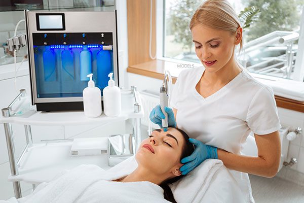 woman applying facial treatment to a patient